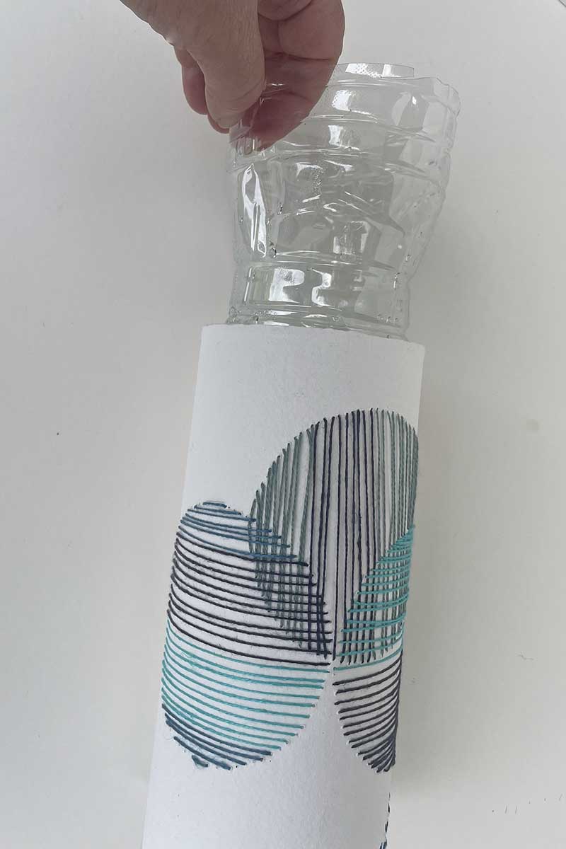 putting plastic bottle into paper embroidered sleeve