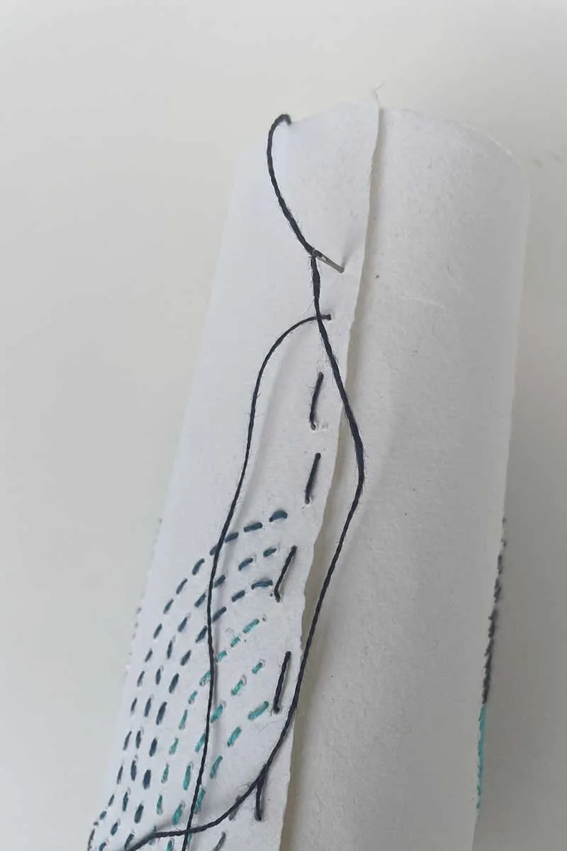 sewing the paper embroidery into a tube to make a handmade vase sleeve