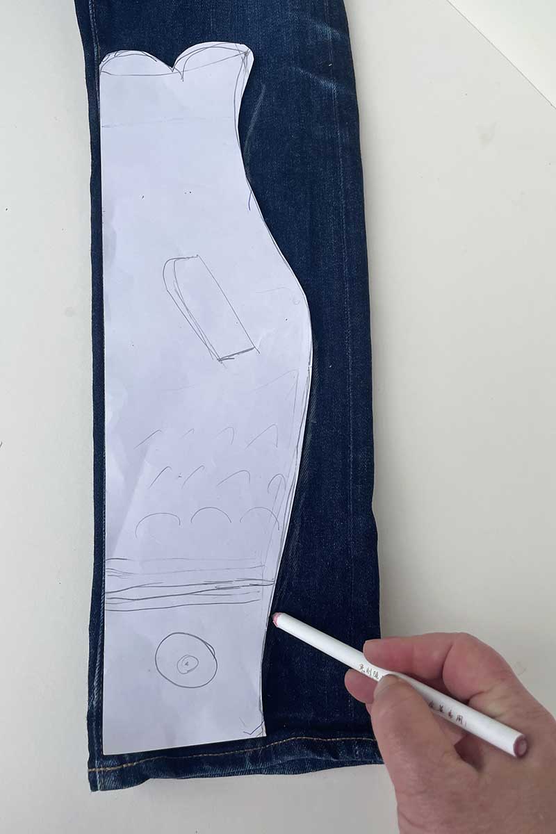 Drawing the DIY windsock fish template onto the denim jeans leg