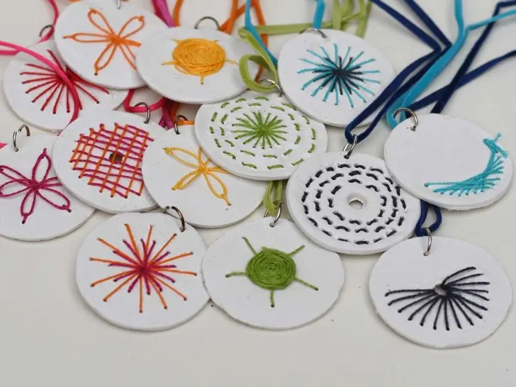 A collection of embroidered clay pendant necklaces in a rainbow of colours
