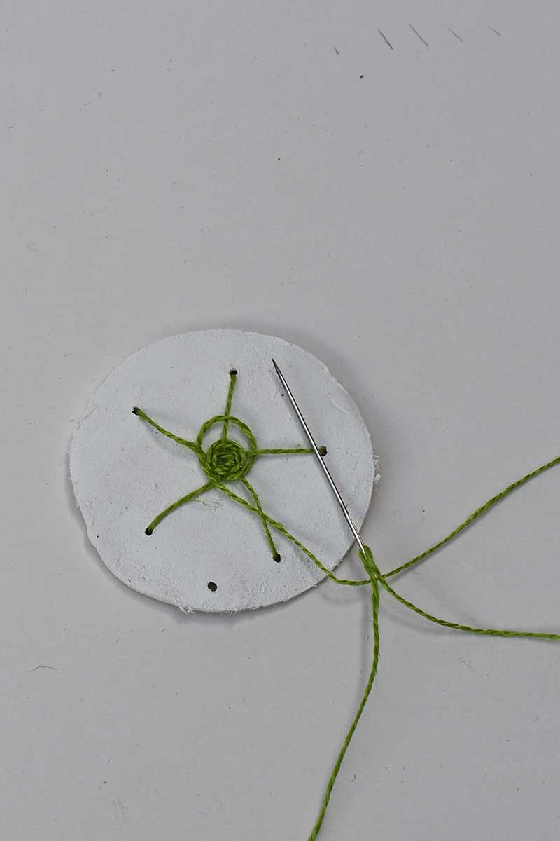 woven web stitch in green on clay disc