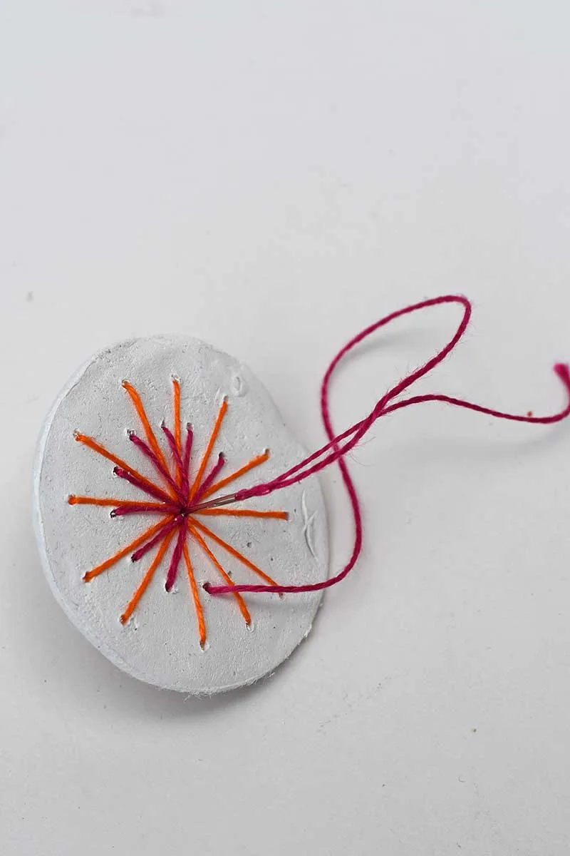 Embroidering sun stitch on clay disc