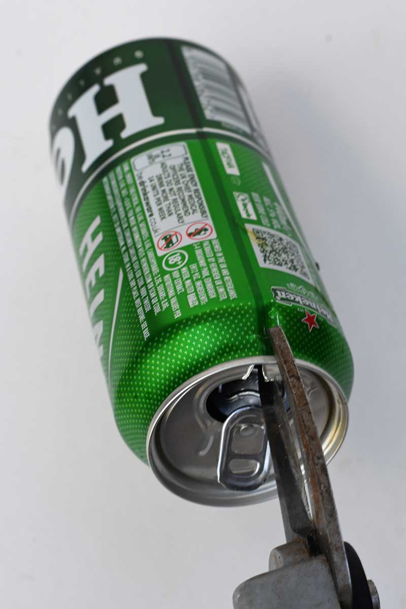 cutting the top of a Heineken Beer can