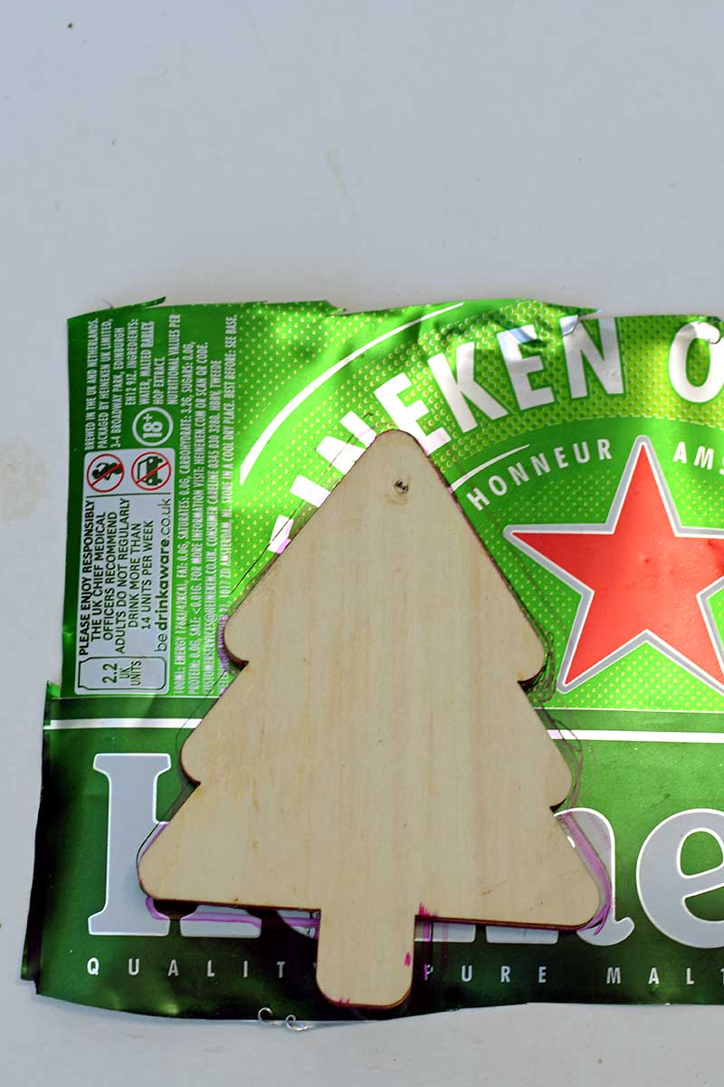 Drawing around a Christmas tree wooden shape on aluminium tin can