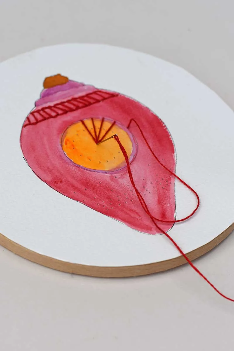 embroidering paper with a hoop red bauble design