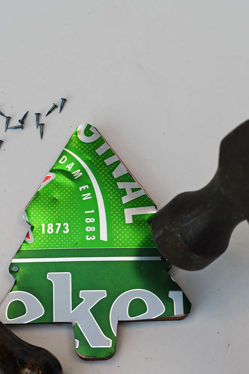 hammering in nails to soda can Christmas tree