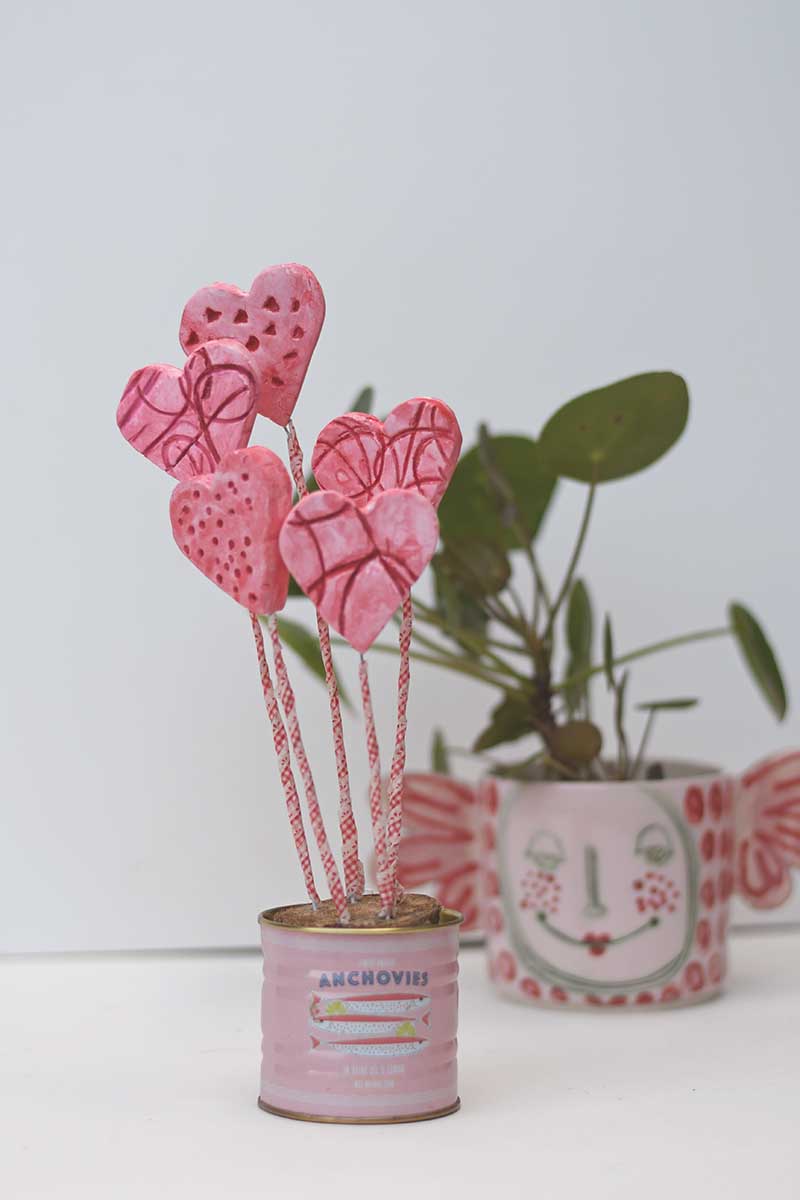 air dry clay hearts in a tin pot with a plant in background