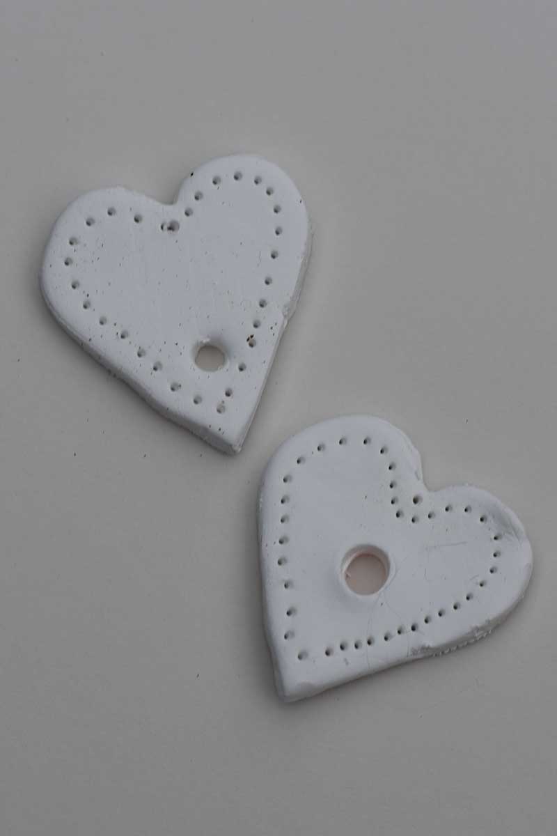 two hole punched air dry clay hearts